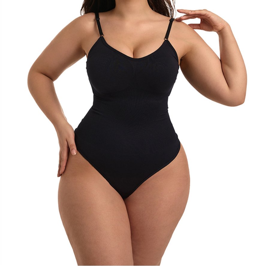 A plus-size model wearing a black ribbed one-piece bodysuit with thin shoulder straps, photographed against a solid white background.